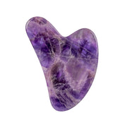 Amethyst roller and gua sha displayed on beauty background

